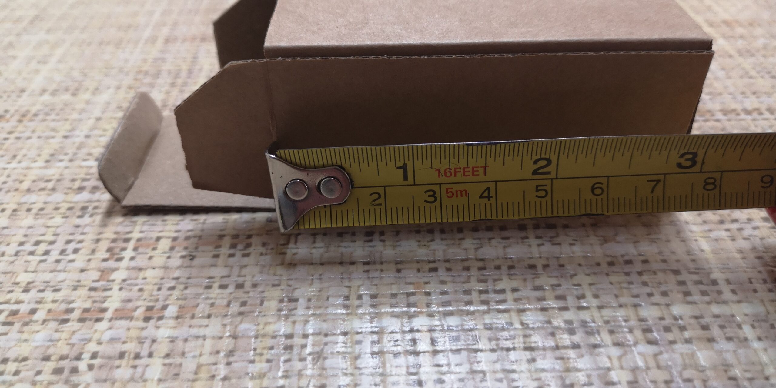 Custom cardboard box placed on packaging plans, showing bespoke packaging design and precise box sizing